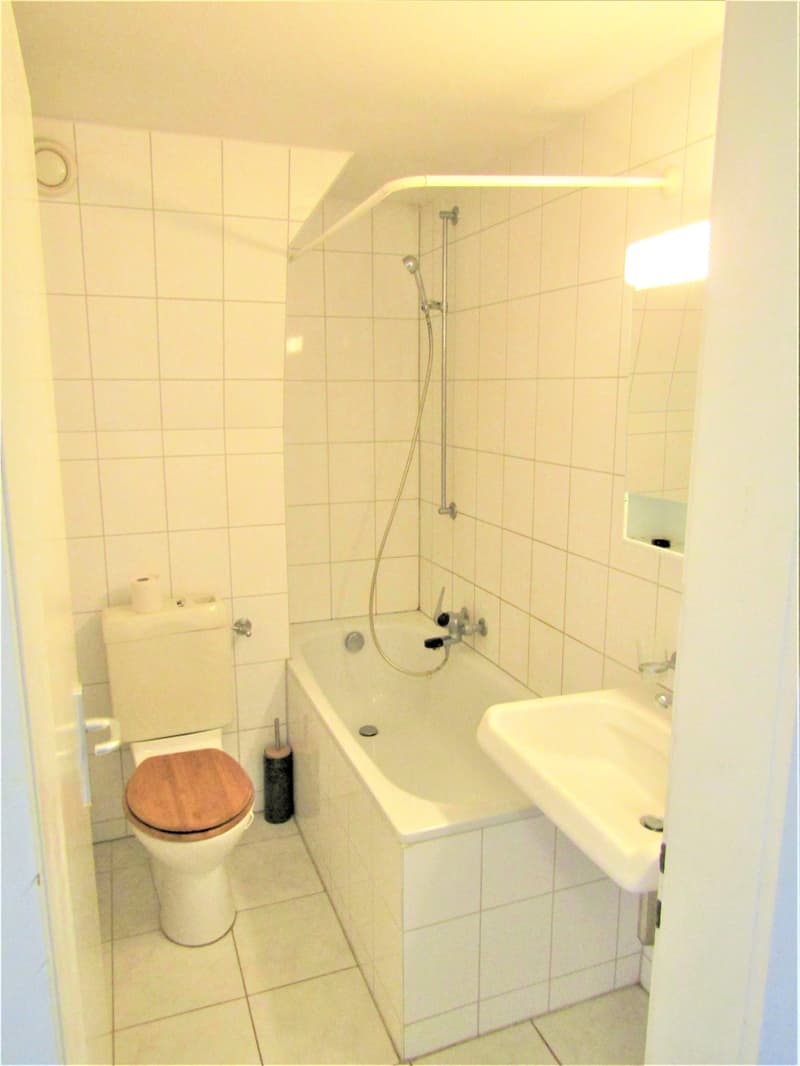 white tiles, white bathtub, white toilet, white sink, shower head, faucets, mirror