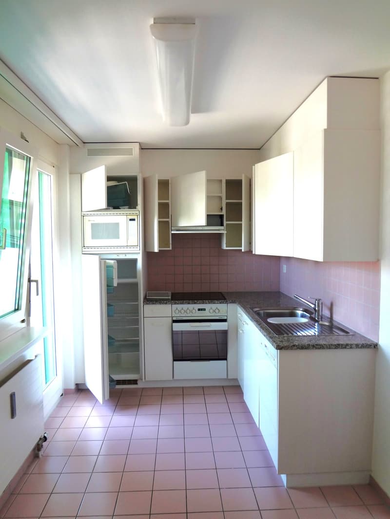Spacious kitchen with white cabinets, granite countertops, tiled floor, and built-in appliances including a dishwasher and oven. The kitchen has a clean, modern design with ample storage space.