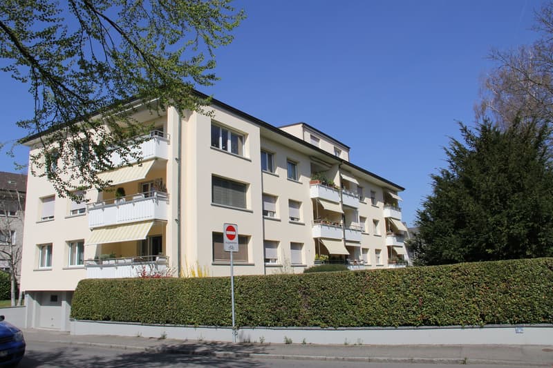 4 story apartment building, balconies, hedges, street sign