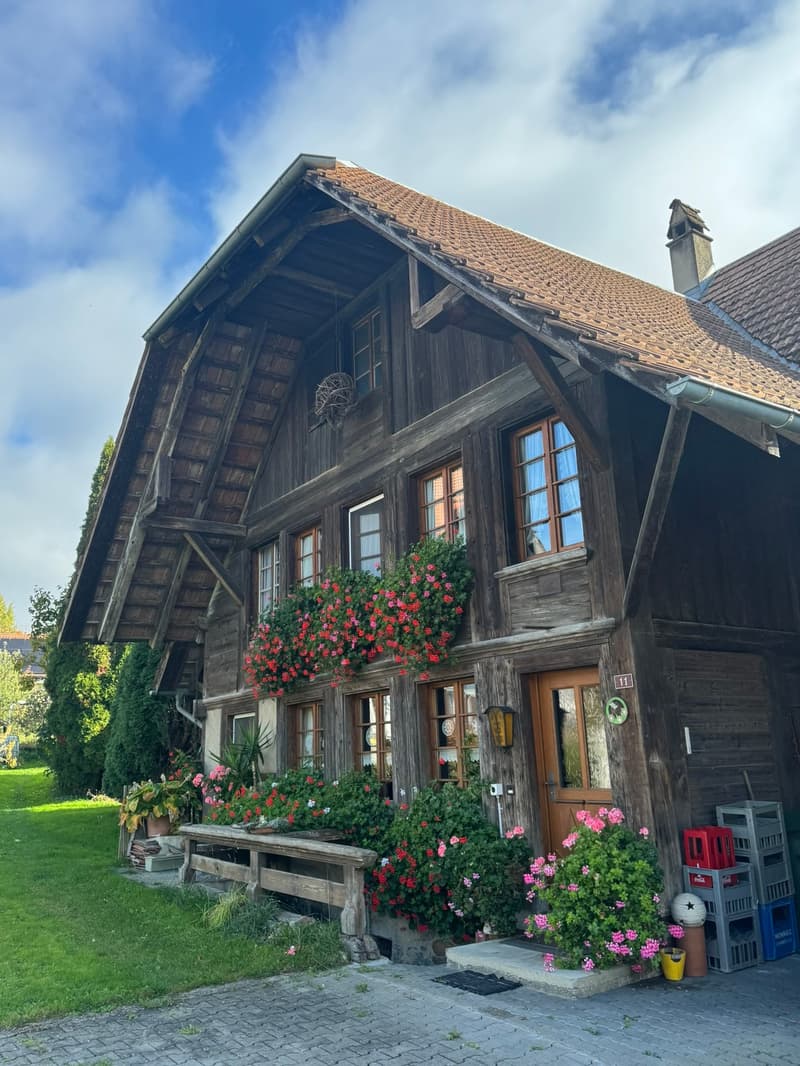 Traditional wooden house, steep roof, wooden beams, large windows, flower boxes, wooden bench, garden, brick pathway