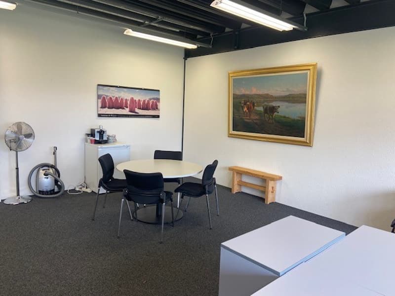 empty conference room with table, chairs, wooden bench, paintings, and a coffee machine