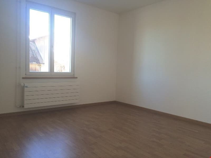 Empty room, white walls, wooden floor, window, and radiator