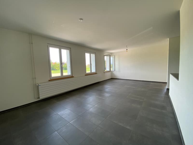 Empty room with white walls, gray tiles, and three windows with white frames