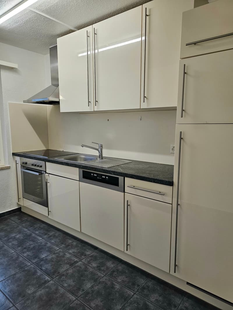 modern kitchen with white cabinets, black tiled floor, granite countertop, stainless steel appliances, under cabinet lighting