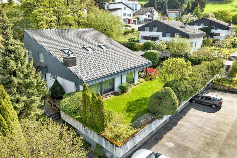 Detached house, gray roof, white walls, large windows, green lawn, car parked in front
