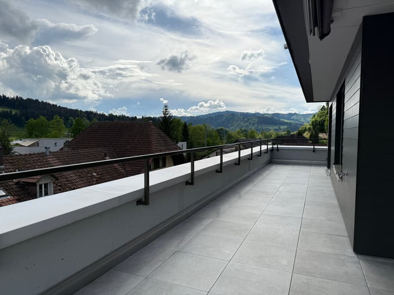 Large balcony with tile flooring, metal railing, and scenic view of the surrounding mountains and forest