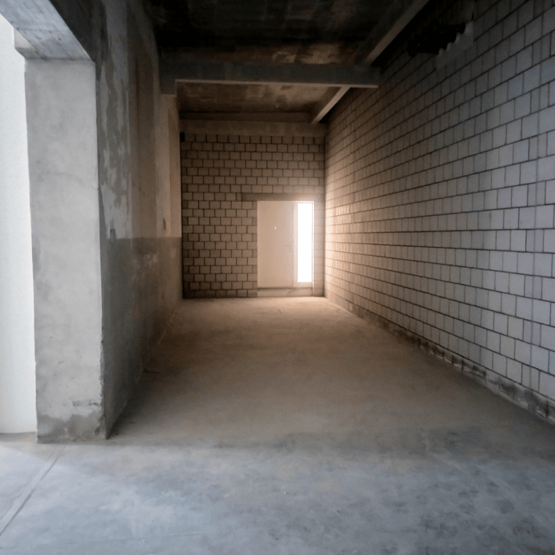 Empty room with brick walls, concrete pillars, cement floor, window and door at the end