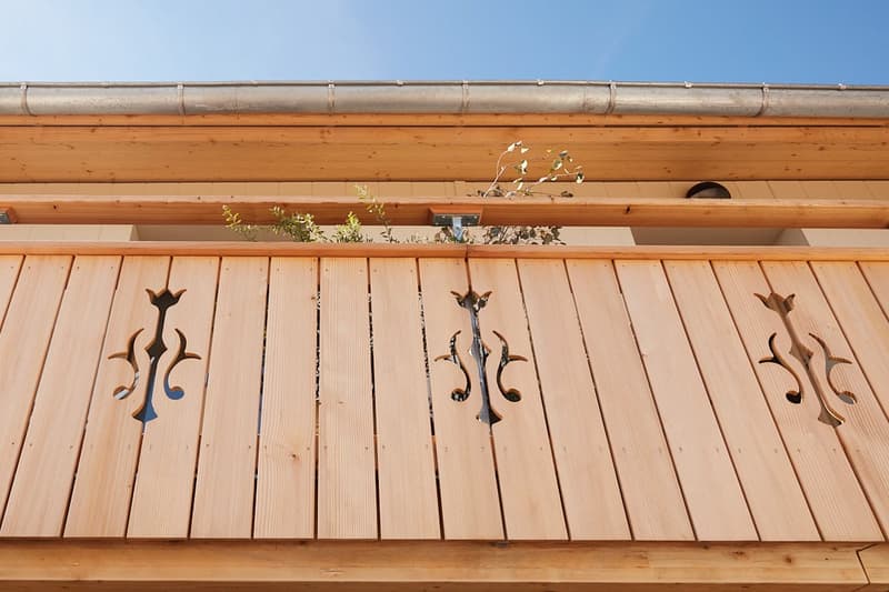 wooden facade with decorative metalwork on balcony