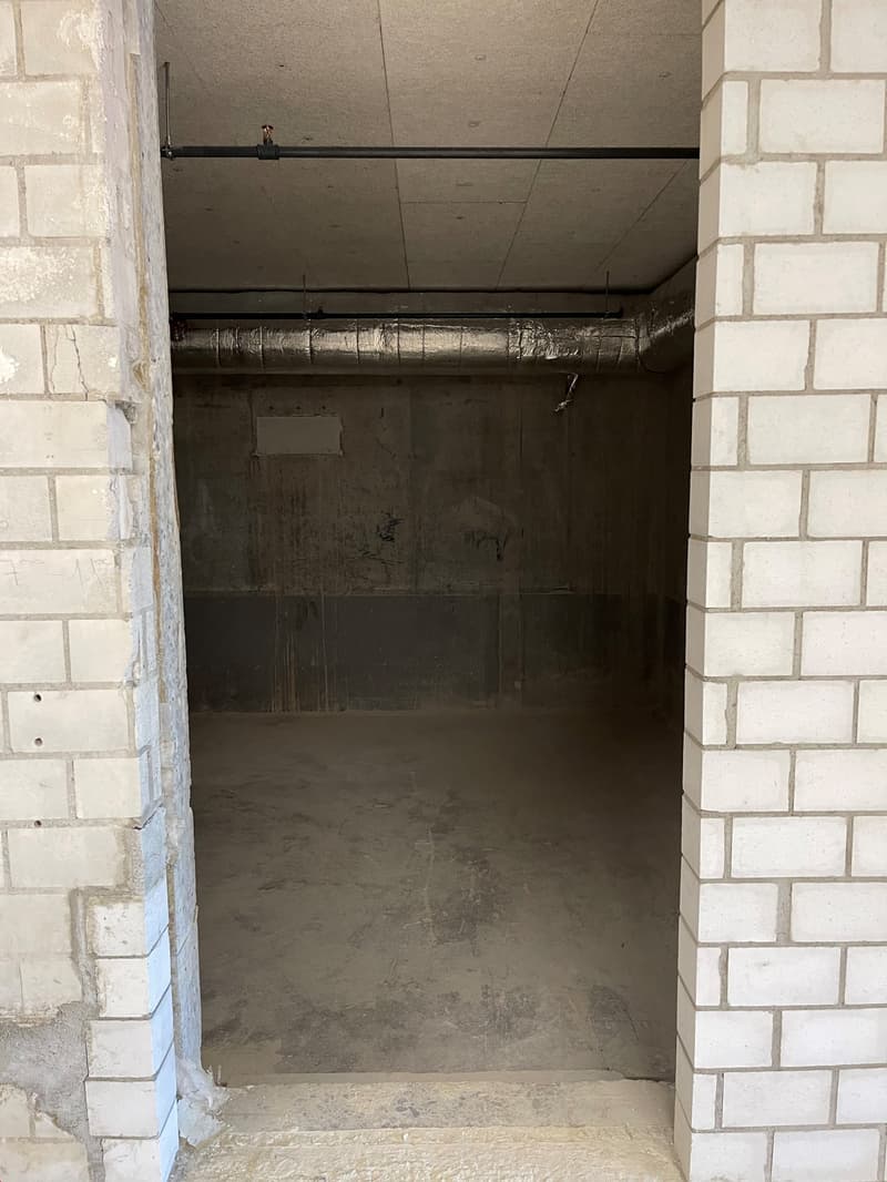 Empty garage space with brick walls, concrete floor, metal pipe