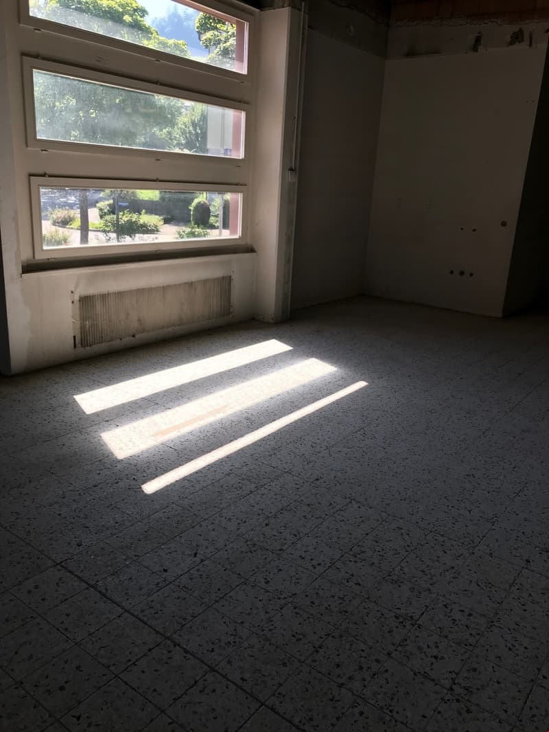 Empty room with large windows, concrete floor, and natural light coming in