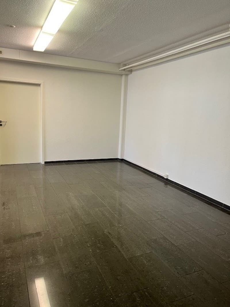 Empty room with white walls, gray tile flooring, and recessed lighting.