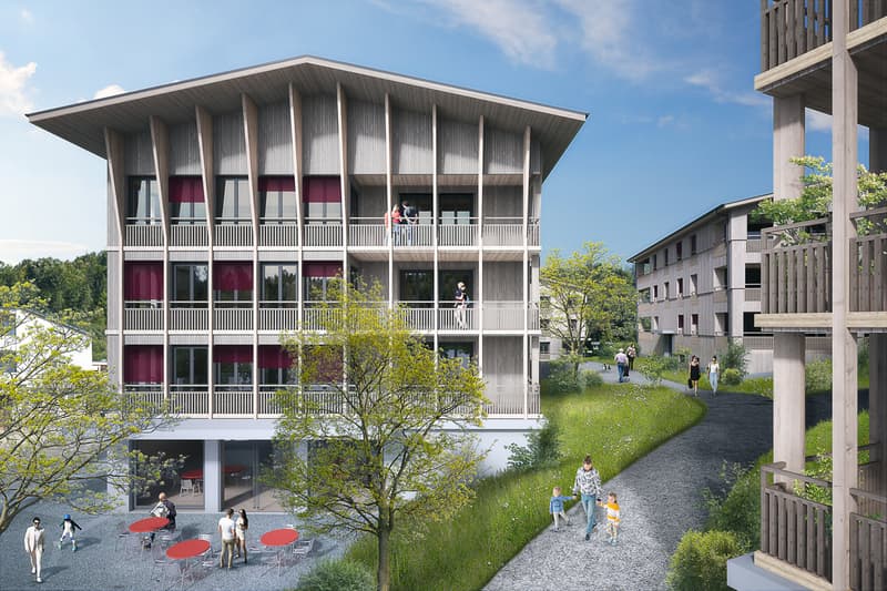 Modern apartment building with balconies, multiple floors, and a landscaped area in front.