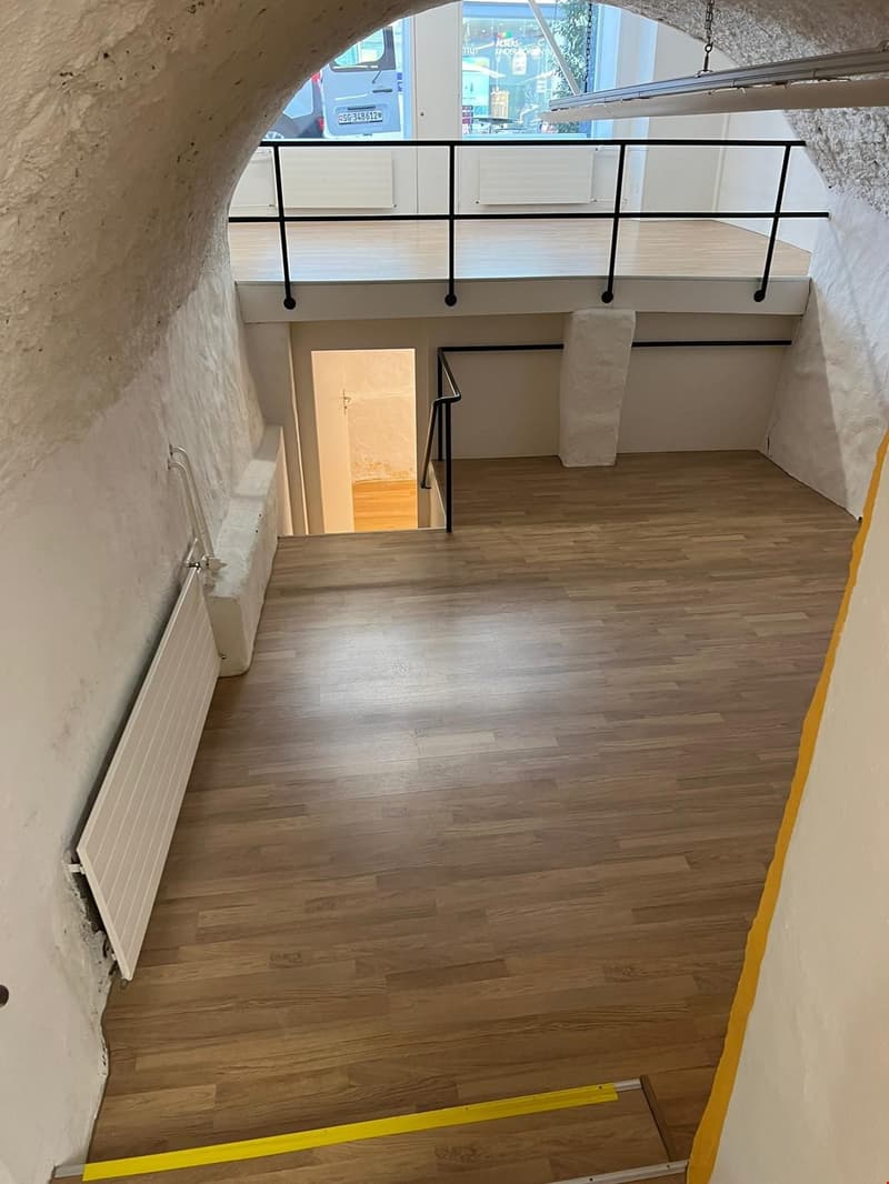 wooden floor, white walls, yellow line, black railing, white pillars, entrance, arch