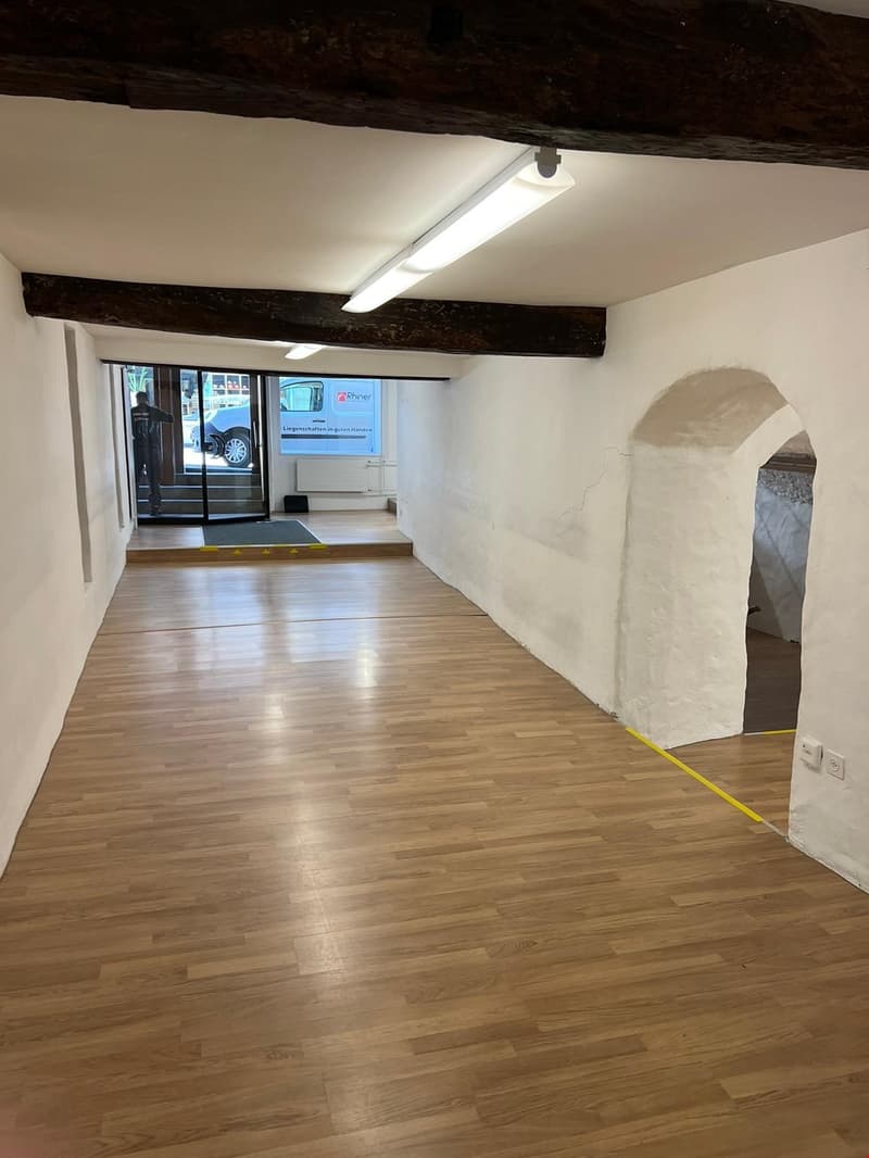empty room with wooden floor, white walls, and two arched passageways