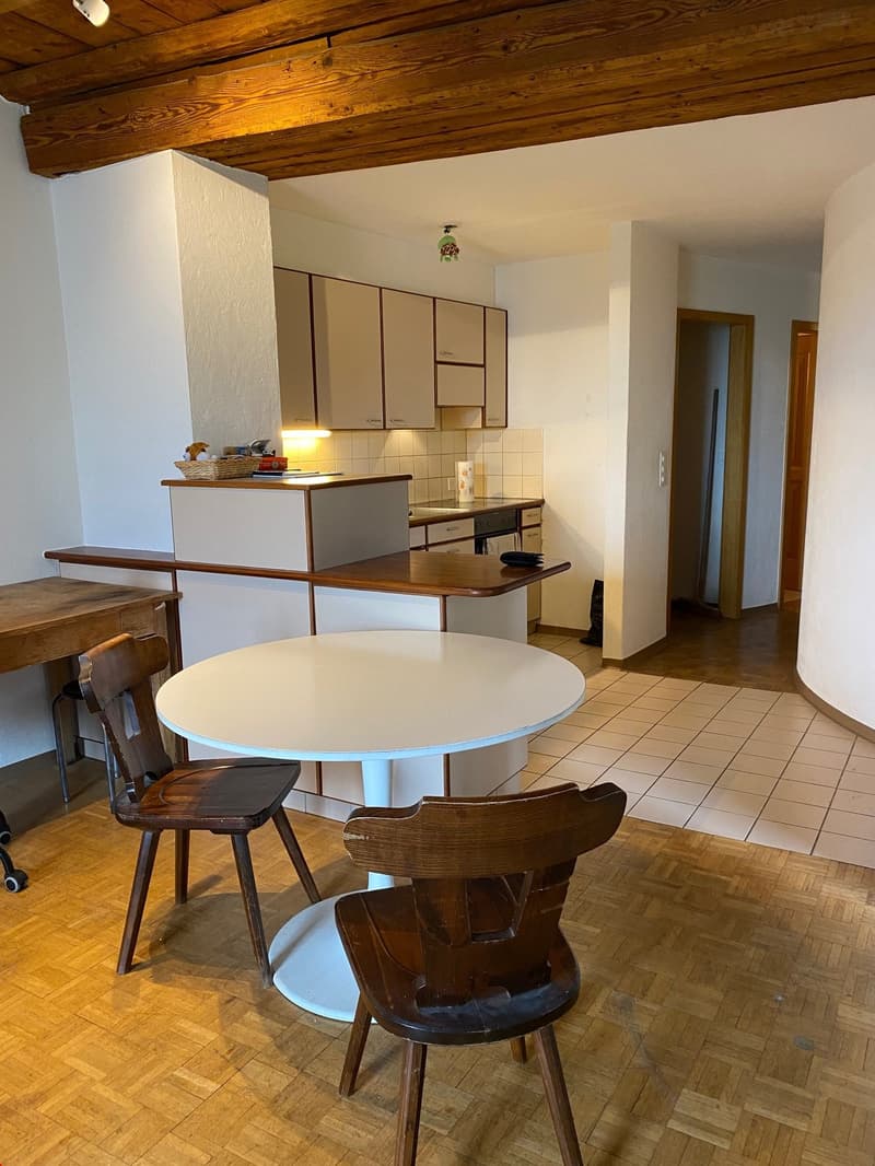 Open-plan kitchen and dining area, wooden flooring, a dining table, chairs, a counter, cabinets, dishwasher, oven, sink, baskets, white walls