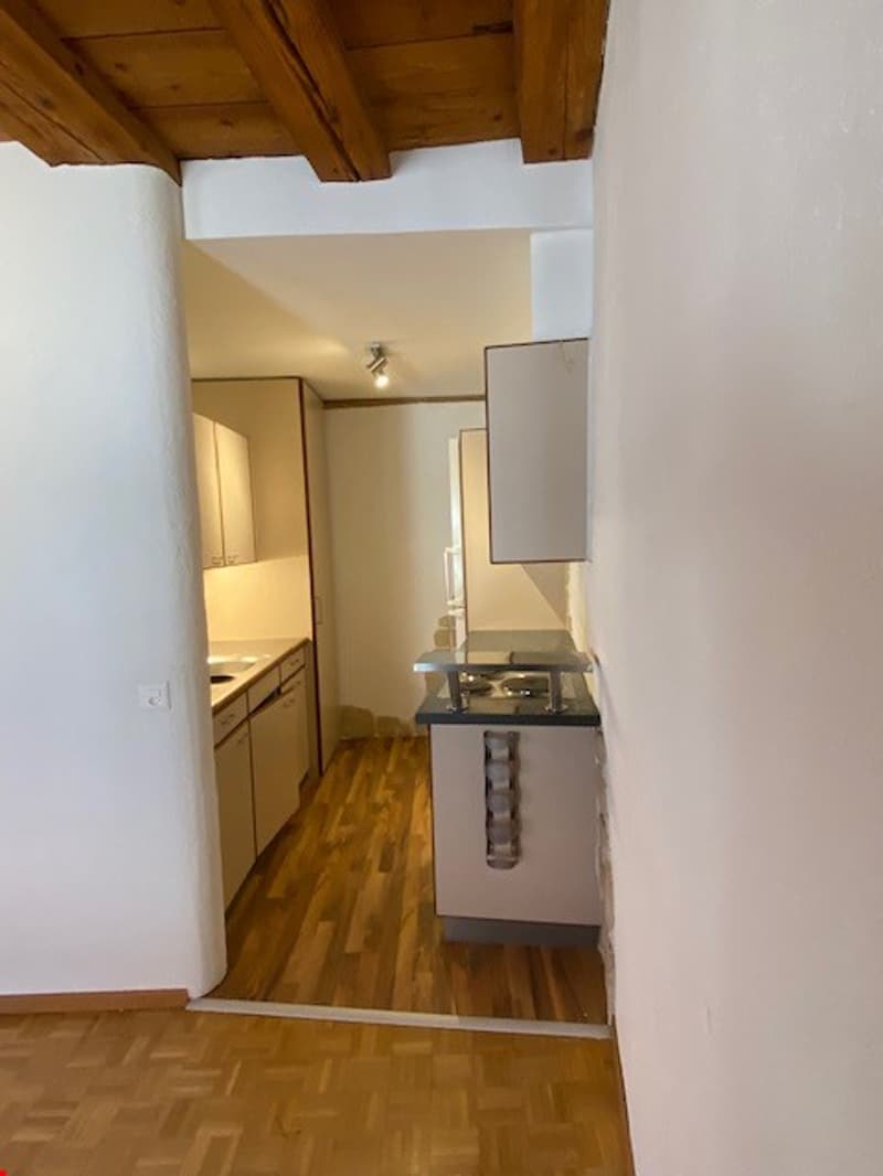Hardwood floor, white walls, kitchen cabinets, countertop, dishwasher
