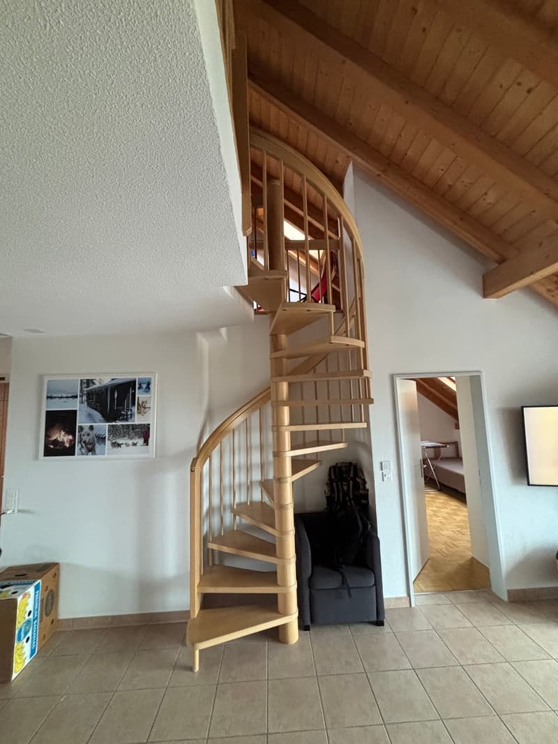 spiral staircase, wooden ceiling, white walls, tiled floor, couch, backpack, photo collage