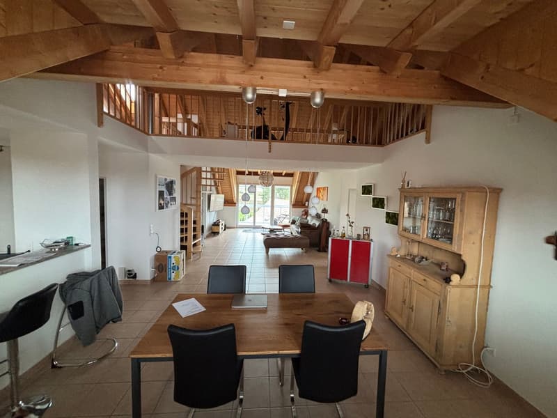 Dining room with wooden table and chairs, wooden ceiling, wooden cabinet, kitchen area, living room with couch and glass door