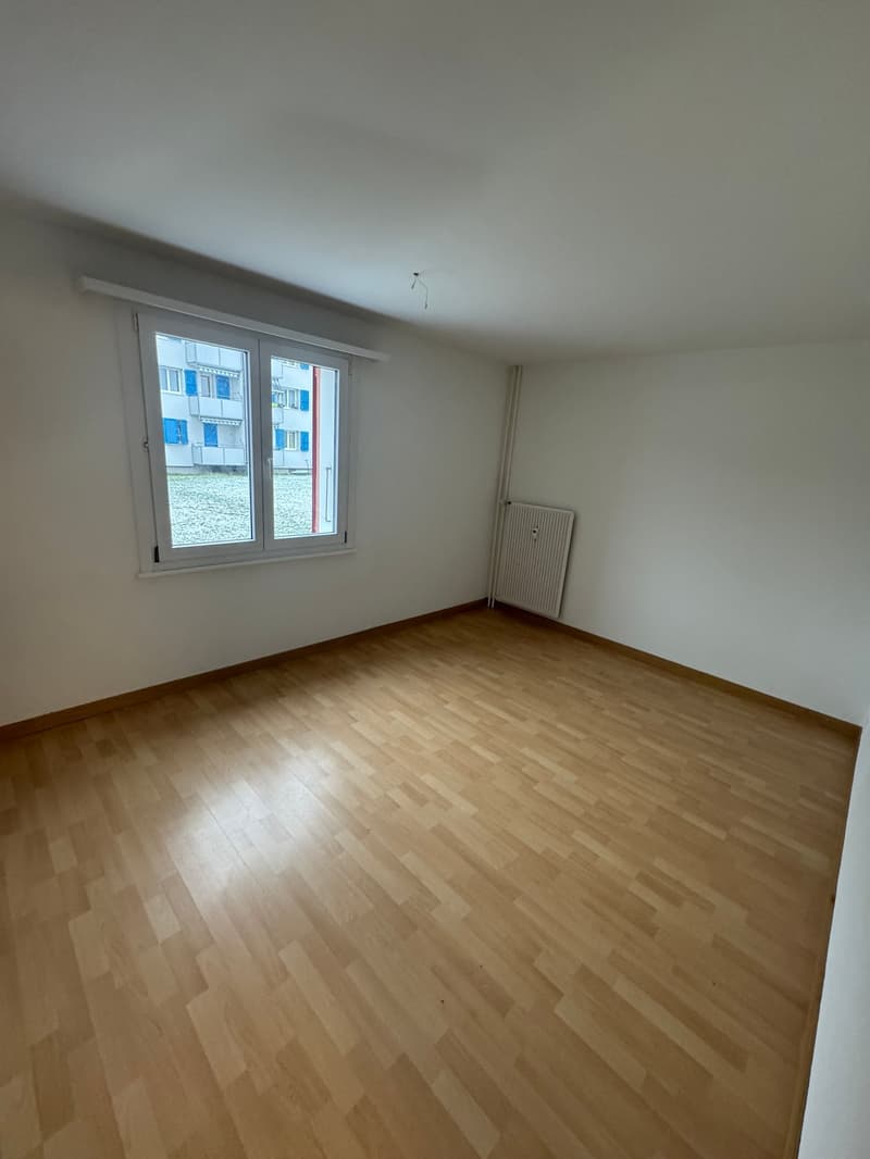empty room, wooden floor, white walls, large window, white radiator