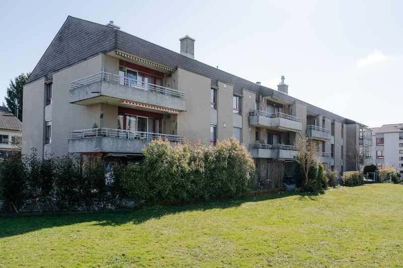 3 story apartment building, balconies, green lawn in front