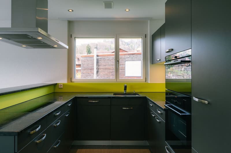 modern kitchen with black cabinets, yellow countertops, stainless steel appliances, large window