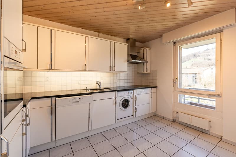 modern kitchen with white cabinets, tiled floor, black countertops, dishwasher, washing machine, sink, faucet, window