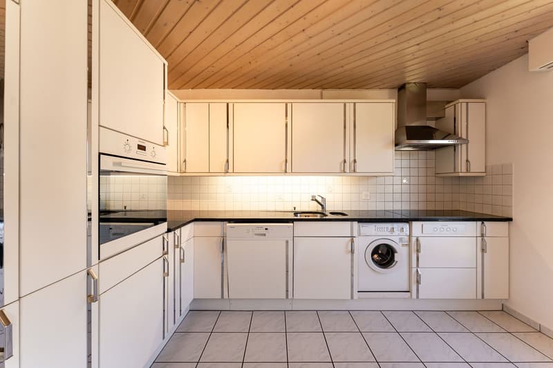 modern kitchen with white cabinets, black countertops, integrated appliances, tiled floor
