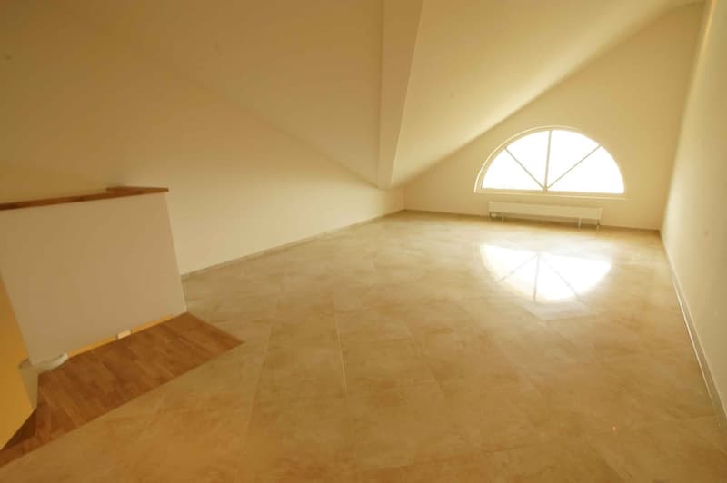 Empty attic room with tile flooring and arched window with balcony