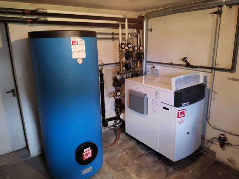 Concrete floor, metal pipes, blue water tank, heating system, white appliance