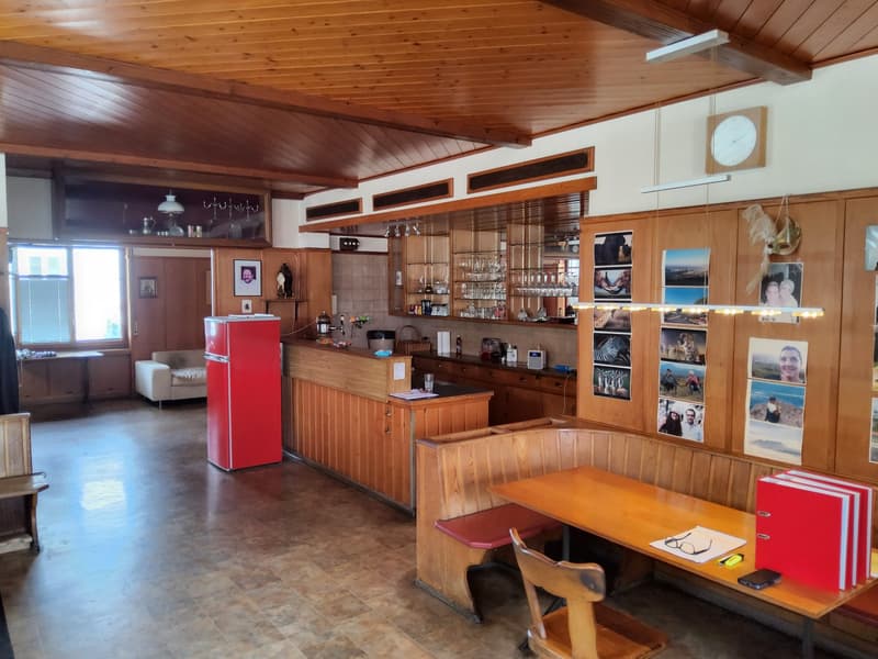 wooden paneled ceiling, red refrigerator, wooden bar counter, built-in wooden cabinets, open counter with kitchen items, wooden dining table, bench seating, pictures on wall, window with blinds