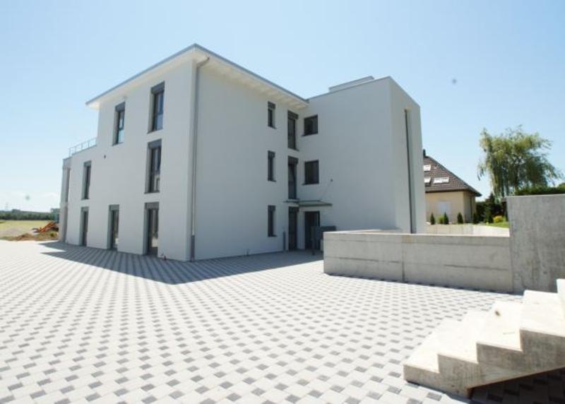 Two-story building, white facade, several windows, steps in front, concrete driveway