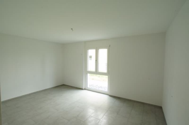 Empty room with white walls and tiled floor, door, and windows
