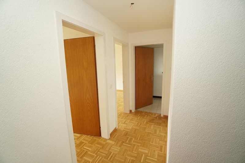 Empty hallway with wooden floors and white walls, two doors