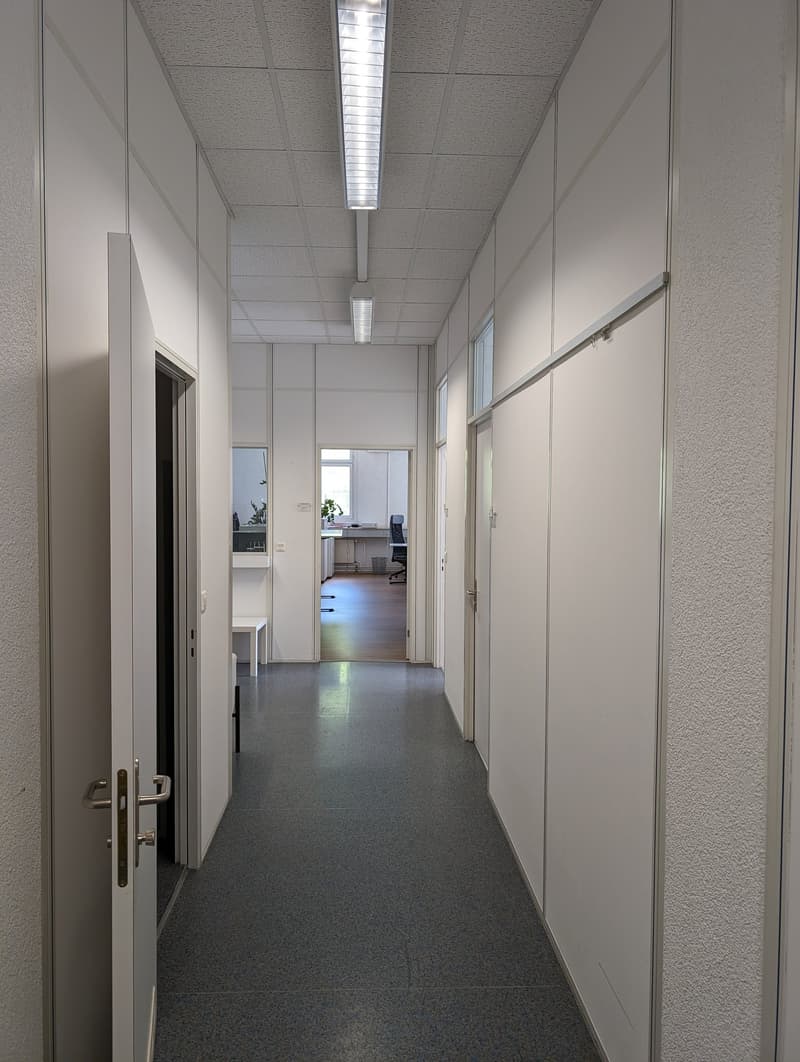 white walls, grey floor, bright fluorescent ceiling lights, doors on either side