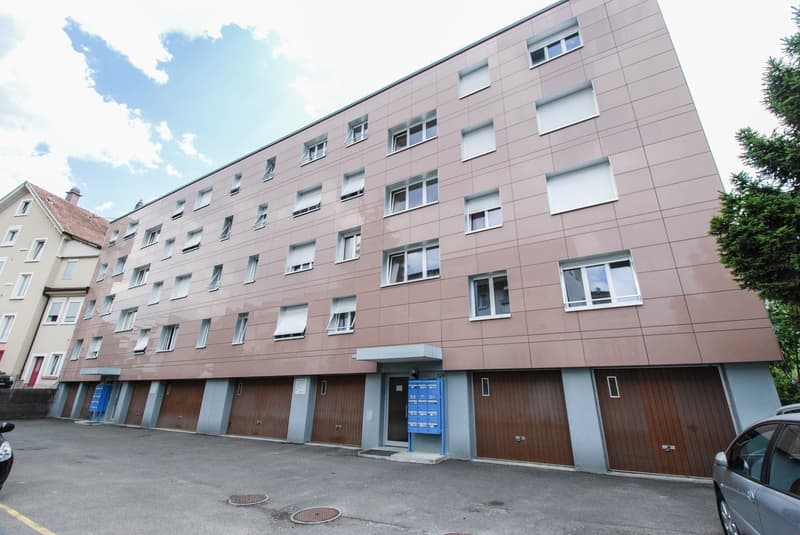 3 story building, brick exterior, multiple garages, multiple windows, mailboxes