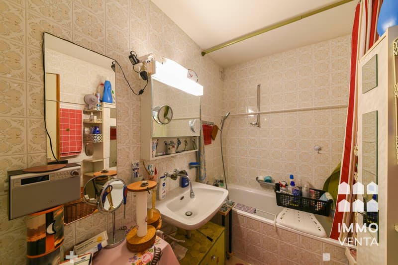 Bathroom with bathtub, sink, mirror, and various toiletries