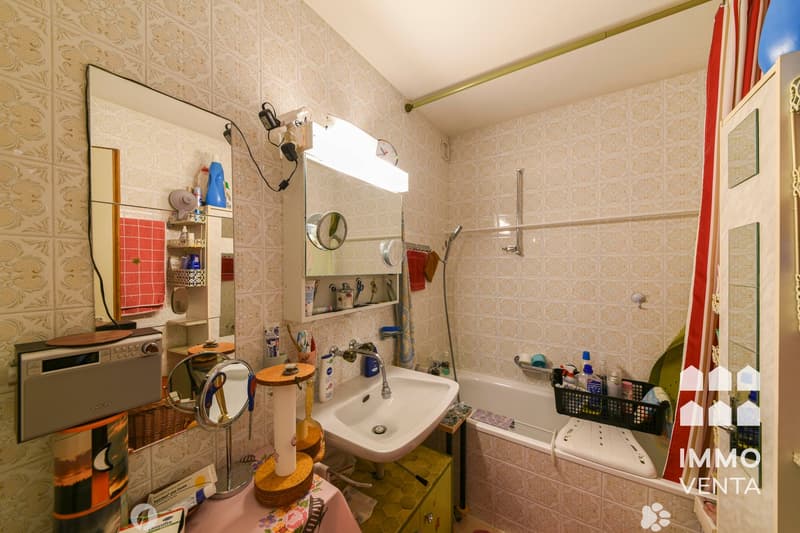 Bathroom with bathtub, sink, mirror, and various toiletries