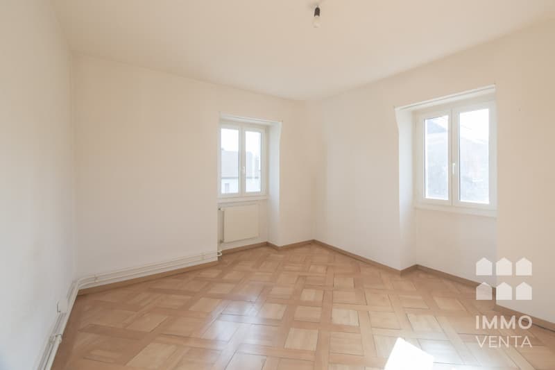 empty room, wooden parquet floor, white walls, two windows, radiator