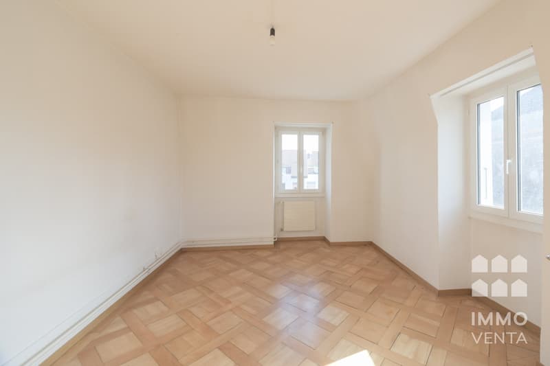 empty room, wooden parquet floor, white walls, two windows, radiator