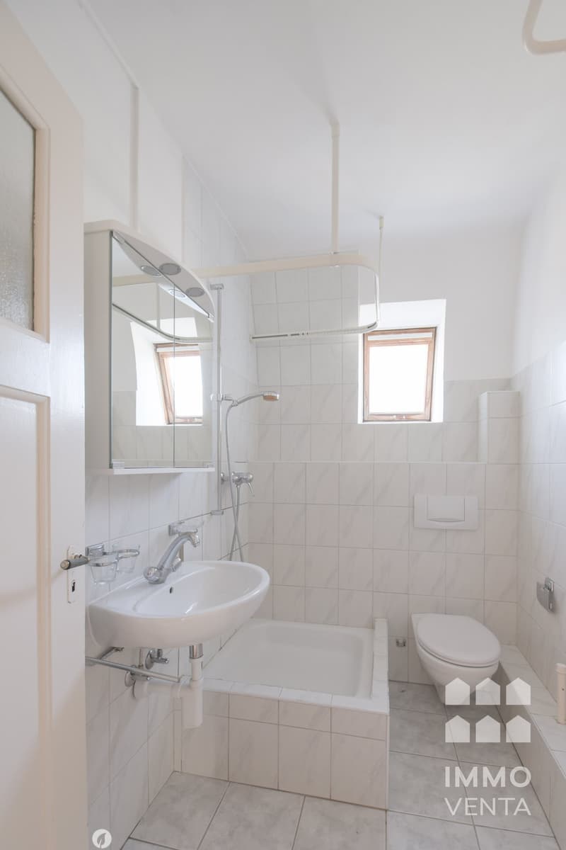 Bathroom with bathtub, sink, toilet, and shower, all white tiles, mirror, and two small windows