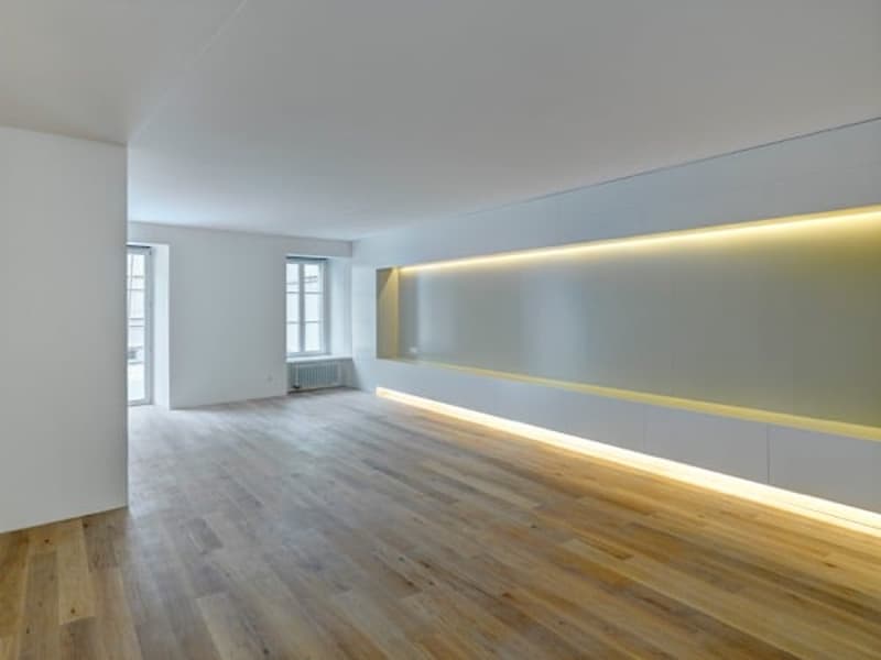empty room, wooden floor, white walls, yellow lighting on wall, windows