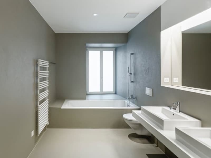 modern bathroom with bathtub, two sinks, toilet, and a window