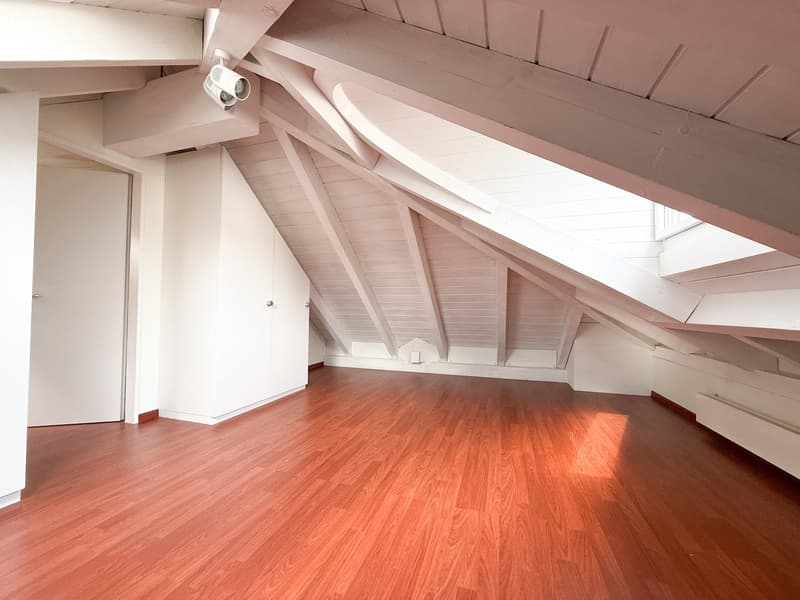 empty attic room, wooden floor, white walls, wooden beams, skylight
