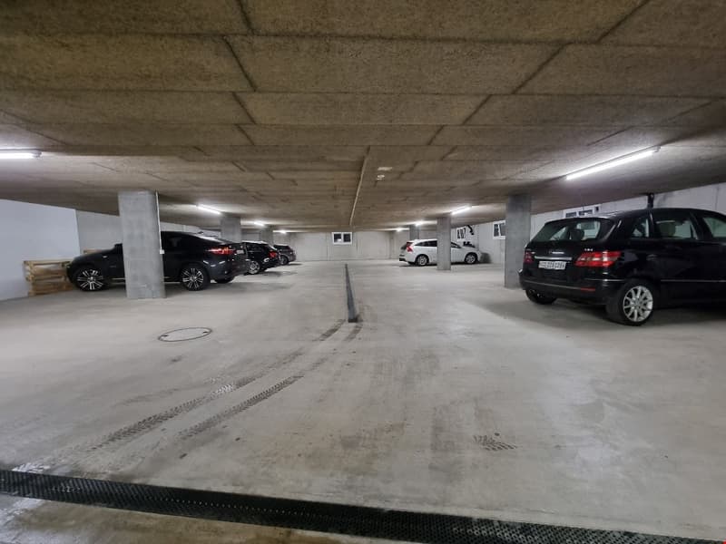 concrete underground parking lot with four cars parked