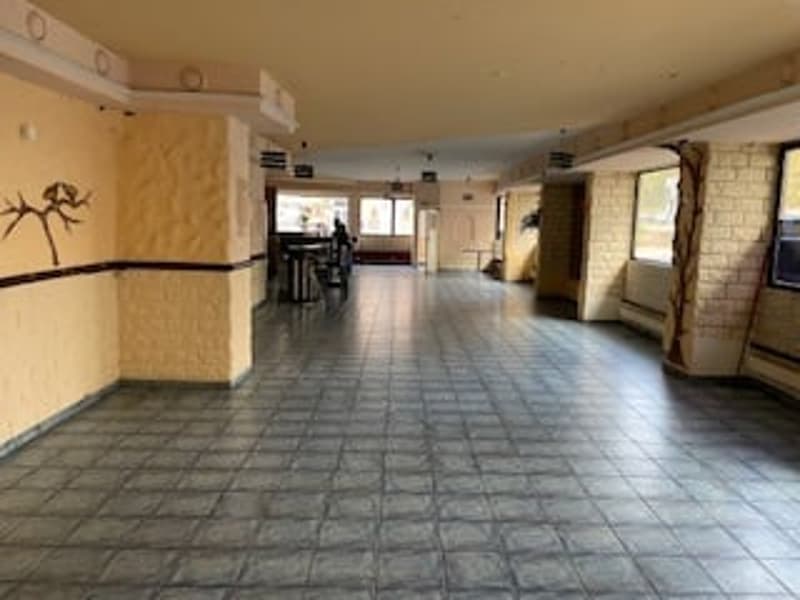Empty room with tiled floor, yellow walls, windows, and a door.