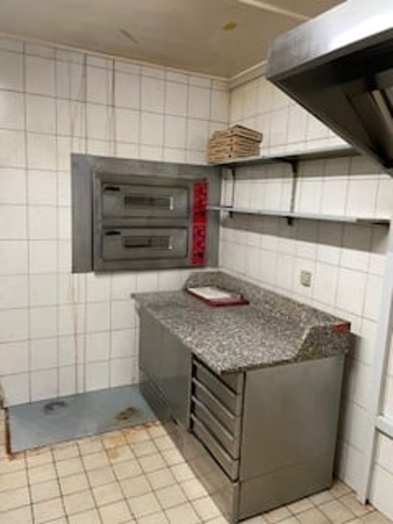Commercial kitchen with oven, countertop, shelves, and stainless steel drawers