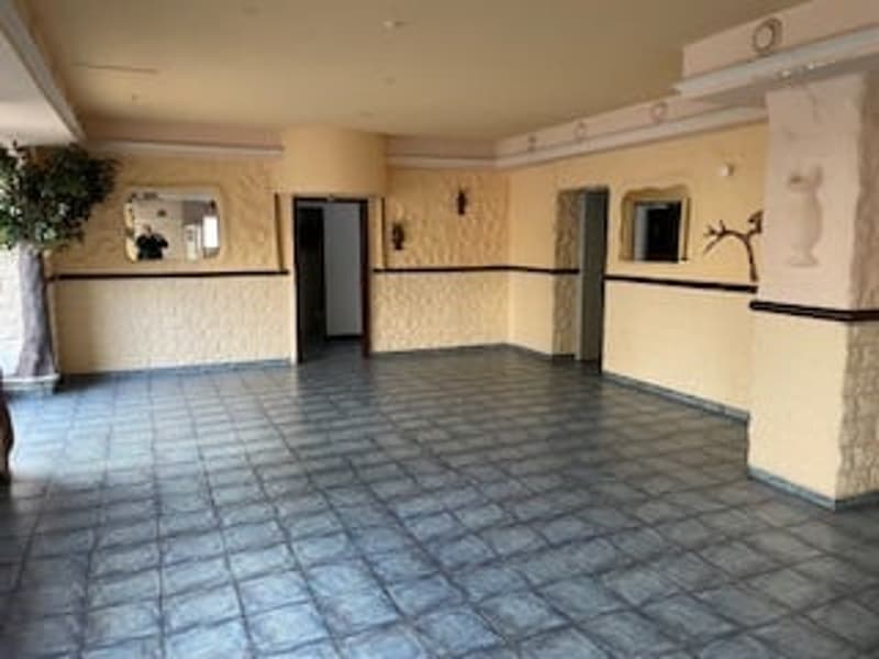 Empty room with tiled floor, yellow walls, two doors, mirror, plant