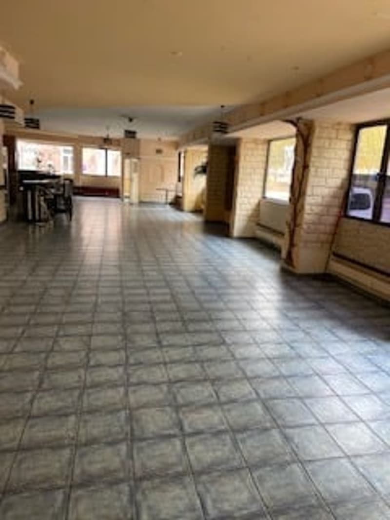 Empty room with tiled floor, large windows, and a door at the end.