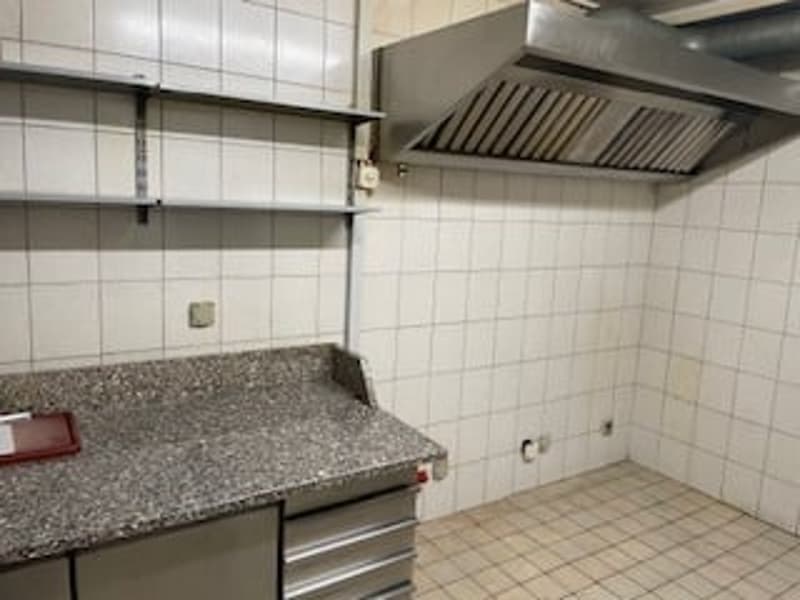 A small kitchen with a granite countertop, stainless steel cabinets, and a stainless steel hood.