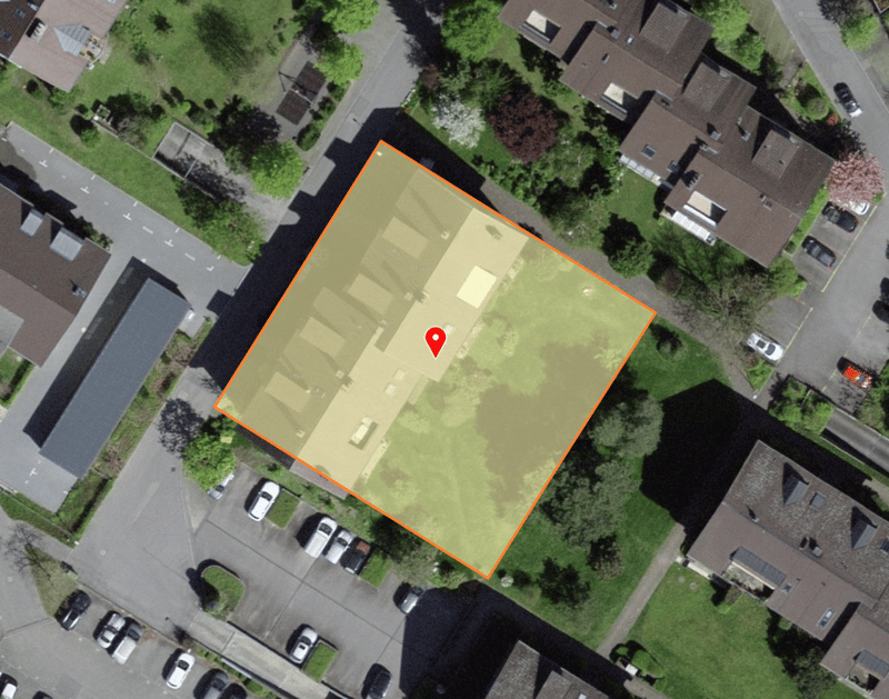 Aerial view of residential area with buildings, cars parked and a marked square indicating a construction site.
